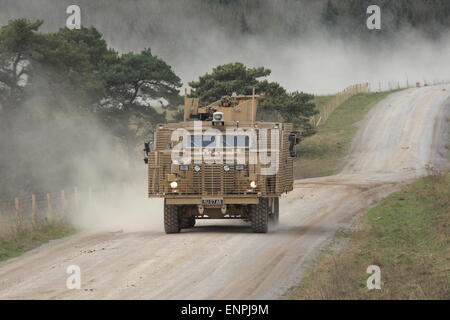 Esercito britannico Mastiff pattuglia su ruote il veicolo viaggia a velocità lasciando una nube di polvere durante l'esercizio. Foto Stock