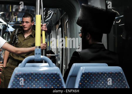 Gerusalemme, Israele. 9 maggio 2015. Un ultra-Ortodosso Ebrei religiosi uomo corse il tram che indossa una pelliccia shtreimel alla sua testa nelle ore serali, come il Sabato Ebraico arriva alla fine. Il shtreimel è indossato da sposato haredi uomini ebraica in giorno di sabato e festività ebraiche come una forma di santificazione. Foto Stock