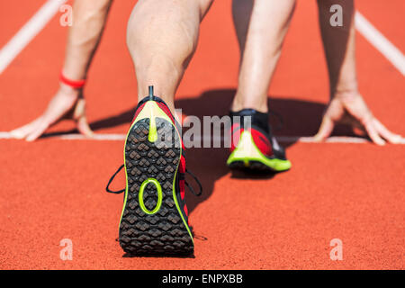 Runner in uno stadio è in posizione di avviamento con le mani sulla linea. Versione non filtrata. Foto Stock