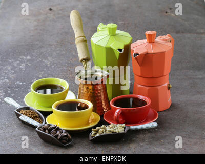 Verde e nero i chicchi di caffè e utensili diversi per caffè bollente (macinino, bollitore, cezve) Foto Stock