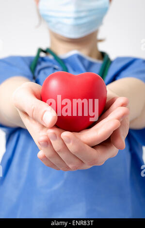 Medico donna tenendo un cuore rosso forma Foto Stock