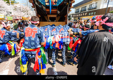 Squadra di uomini che lottano per spingere un enorme dashi, yama, galleggiante di legno, circondato da folle di turisti che guardano al festival della primavera Inuyama Foto Stock