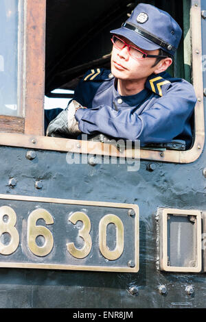 Kyoto. Giovane giapponese, autista del treno che si addormenti e guarda davanti al taxi di una locomotiva a vapore al museo della locomotiva di Umekoji. Foto Stock