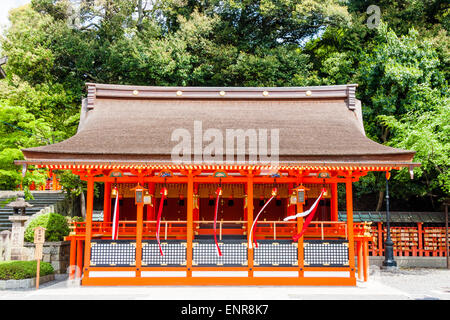 Piccolo sub-santuario vermiglio con corde campanili che soffiano nel vento, presso il famoso santuario Fushimi inari-taisha Shinto a Kyoto, Giappone. Foto Stock