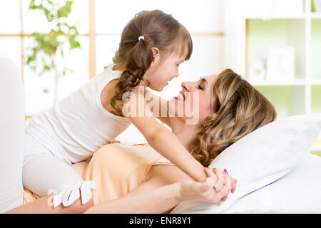 Felice la madre e il bambino ragazza abbracciando e baciando nel letto Foto Stock