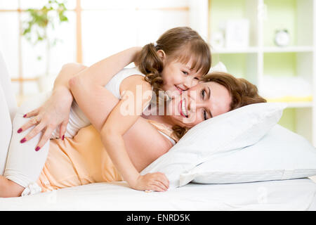 Felice la madre e il bambino ragazza abbracciando e baciando nel letto Foto Stock