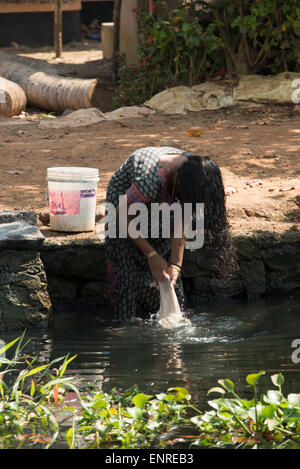 Un abitante di un villaggio il suo lavaggio biancheria nelle lagune del Kerala nel sud-ovest dell'India Foto Stock