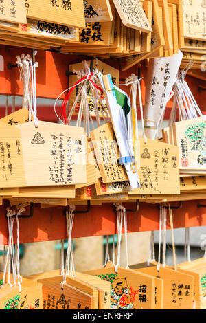 Tavole ema giapponesi, tavolette di desiderio, appese da telaio lavoro da corde rosse in un santuario Shinto. Su di essi sono scritte speranze, desideri e dediche. Foto Stock