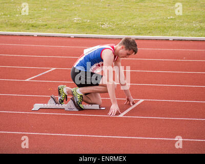 Un runner sui blocchi di partenza ad una pista di atletica Foto Stock