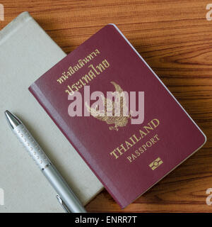 Passaporto thai con i notebook su legno sfondo tabella Foto Stock