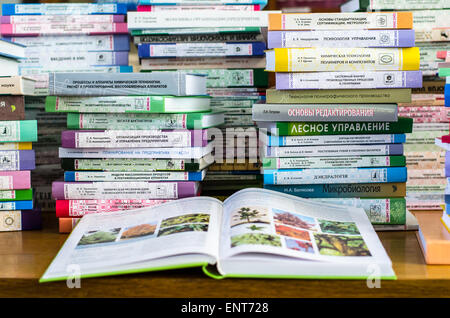 Una ragazza sono trasportano informazioni sulle pile di libri e chiedendo circa i buoni contrassegni Foto Stock