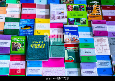 Una ragazza sono trasportano informazioni sulle pile di libri e chiedendo circa i buoni contrassegni Foto Stock
