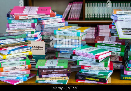 Una ragazza sono trasportano informazioni sulle pile di libri e chiedendo circa i buoni contrassegni Foto Stock