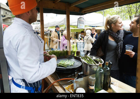 London street market food stallo, Southbank Centre di Londra. Fornitore preparazione e vendita di asparagi freschi ai clienti in coda. Foto Stock