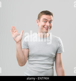 Giovane uomo caucasico mostra messaggio scritto sulla sua mano e sorridente Foto Stock