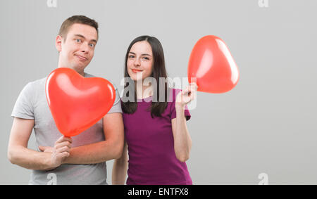 Amorevole coppia giovane azienda cuore palloncini sagomati e sorridente. copia di spazio disponibile Foto Stock