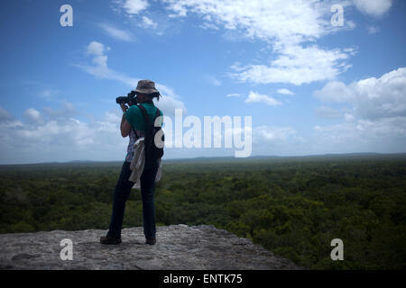 Un fotografo prende le immagini della giungla della parte superiore di un tempio nella città maya di Calakmul, in Calakmul Riserva della Biosfera, stato di Campeche, la penisola dello Yucatan, Messico Foto Stock