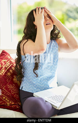 Sottolineato ragazza utilizzando laptop online Foto Stock