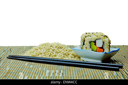 Naturale di materie organiche e cuocere il riso sushi con bacchette sul tappetino di bambù con sfondo bianco Foto Stock