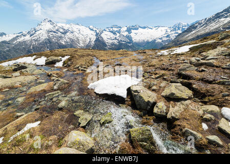 Piccoli torrenti di montagna da neve di fusione che fluisce in un idilliaco ambiente incontaminato. Nevato mountain range. Foto Stock