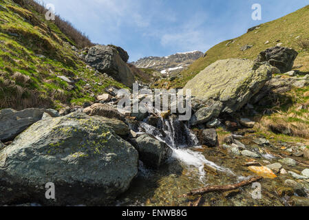 Piccoli torrenti di montagna da neve di fusione che fluisce in un idilliaco ambiente incontaminato. Nevato mountain range. Foto Stock