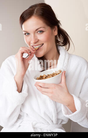 Donna in accappatoio tenendo la coppa con i cereali per la prima colazione Foto Stock