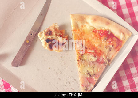 Trancio di pizza e Fast Food avanzi di cibo in scatola di cartone sul tavolo da cucina, stile retrò immagine dai toni Foto Stock