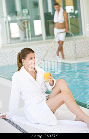 Piscina - giovane donna potrete rilassarvi sul bordo della piscina Foto Stock
