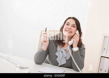 Sorridente business giovane donna al telefono in ufficio Foto Stock