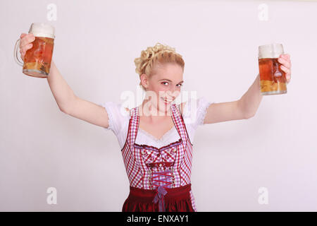 Giovane donna nel grembiule pieno di due boccali di birra Foto Stock