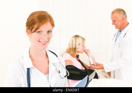 I medici dare da bere paziente braccio rotto Foto Stock