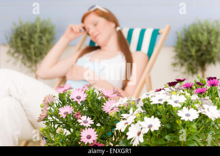 Terrazza estiva con i capelli rossi donna in relax con sdraio Foto Stock