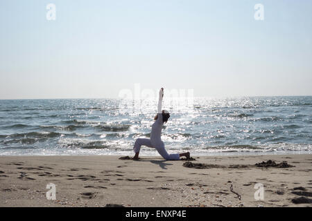 Donna matura la pratica dello Yoga pone sulla spiaggia sabbiosa Foto Stock