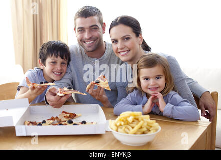 I genitori e i bambini a mangiare la pizza e patatine a casa Foto Stock