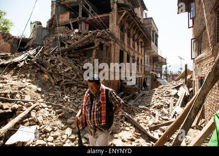 Un uomo cammina attraverso le macerie delle case danneggiate dal terremoto nel villaggio di Sankhu vicino a Kathmandu, Nepal. Foto Stock