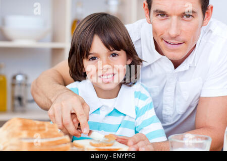 Ritratto di un padre e suo figlio marmellata di spandimento sul pane Foto Stock