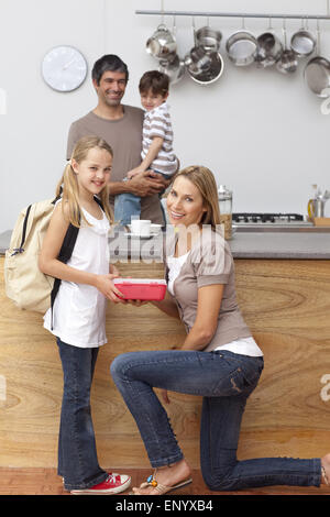 Sorridente madre figlia dando la scuola il pranzo Foto Stock
