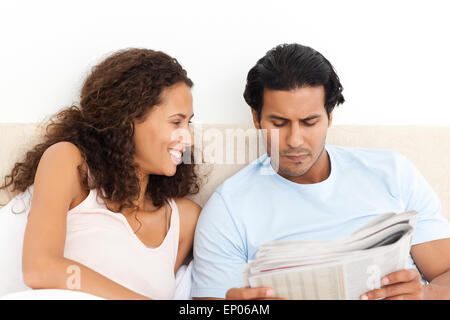 Donna felice guardando il suo ragazzo serio leggendo il giornale Foto Stock