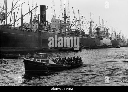 Eine Kleine Barkasse sucht ihren Weg an den großen Schiffen vorbei im Hafen von Hamburg, 1950er Jahre. Un po' di barge sul suo modo Foto Stock