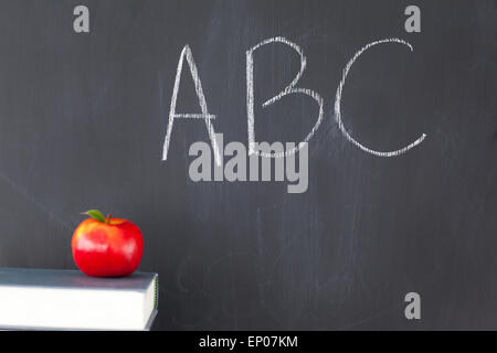 Pila di libri con una mela rossa e una lavagna con ABC scritto su di esso Foto Stock