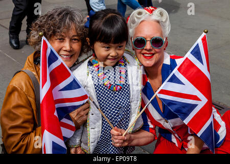 Una donna che indossa una bandiera europea pone in costume con i turisti in Trafalgar Square in occasione del settantesimo anniversario del giorno ve, Londra, Inghilterra Foto Stock