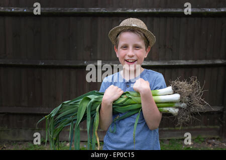 Un ragazzo felice con freschi coltivati i porri organico prelevato dal giardino Foto Stock