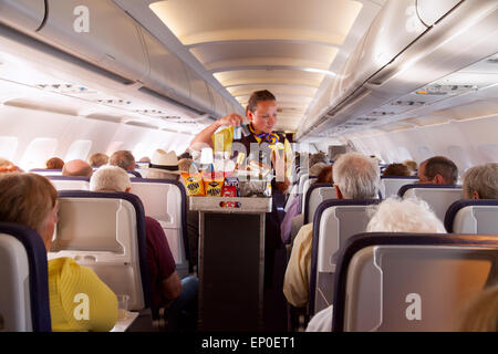 Un assistente di volo membro dell' equipaggio di cabina che serve cibo su un Monarch Airlines aereo da Madera verso l' aeroporto di Gatwick, Regno Unito Foto Stock