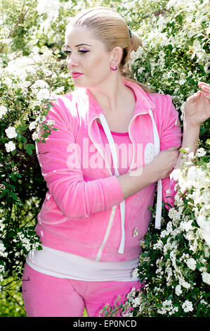 La bella ragazza in un abito rosa tra la fioritura bush Foto Stock