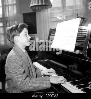 Ein Junge spielt un einem Flügel, Amburgo 1956. Un piccolo ragazzo giocando un pianoforte a coda. Foto Stock