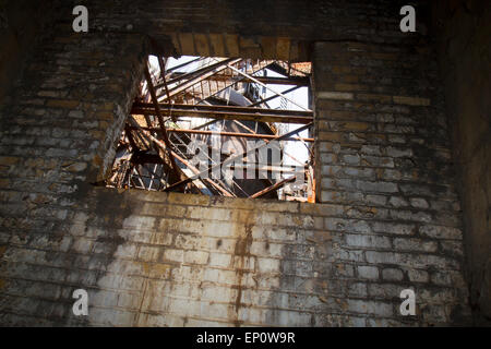 Acciaio arrugginiti altoforno visto attraverso th finestra di un edificio decadente. Foto Stock