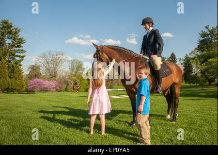 Donna seduta su un cavallo mentre una ragazza e un ragazzo di pet cavallo nella contea di Baltimore, MD USA Foto Stock