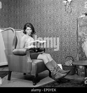Norwegische Schlagersängerin Wencke Myhre sitzt im Wohnzimmersessel Mit einem Buch, 1960er Jahre. Norwegian schlager cantante Foto Stock