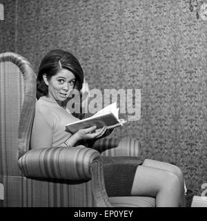 Norwegische Schlagersängerin Wencke Myhre sitzt im Wohnzimmersessel Mit einem Buch, 1960er Jahre. Norwegian schlager cantante Foto Stock