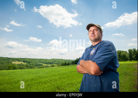 Uomo in piedi con le braccia incrociate sulla terra agricola in Honesdale, PA. Foto Stock